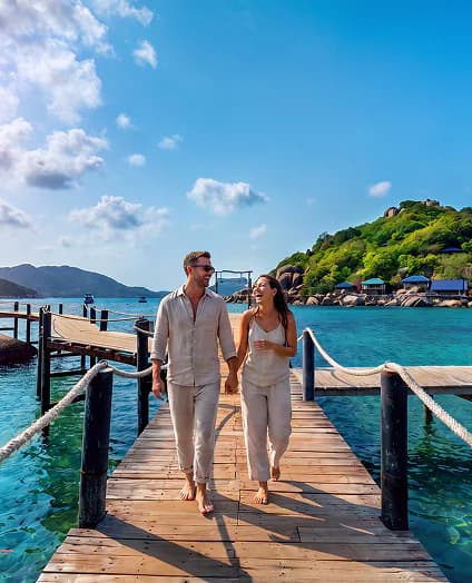Couple walking along a wooden pier over turquoise water